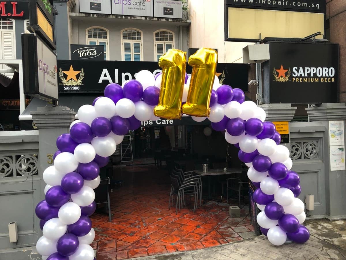 Purple and white balloon arch at a cafe entrance