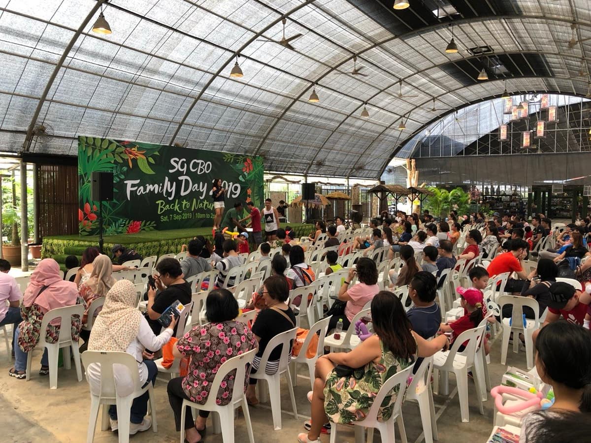 Corporate family day crowd seated at a greenhouse venue