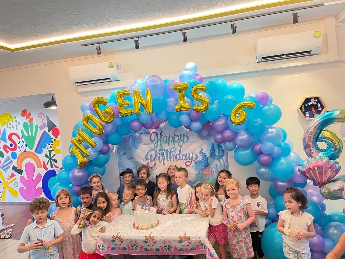 Group at a birthday event with a balloon number arch